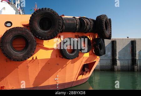 Bow of a tug boat with  bright orange hull moored in a port Stock Photo