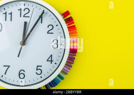The watch and palette of colors for manicureons on tips stands under the clock all standing on a yellow background Stock Photo