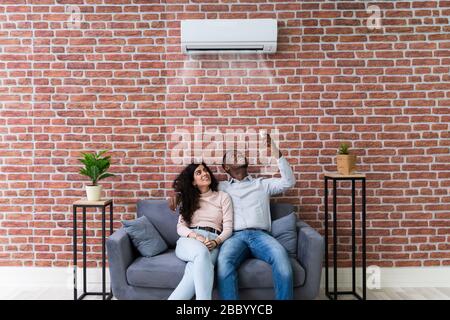 Young Happy Couple Sitting On White Sofa Stock Photo