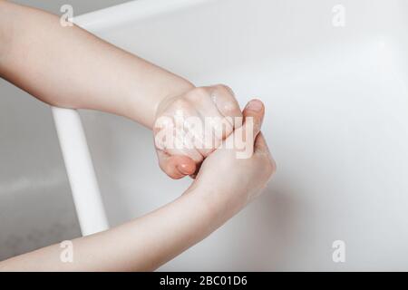 The child washes his hands thoroughly in the home bathroom. Stock Photo