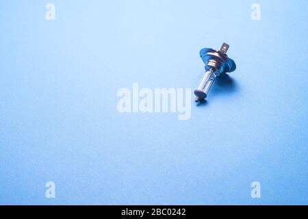 Halogen bulb. H4 car light for lighting when driving. Isolated on a blue background. Stock Photo