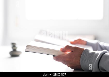 Reading a book with the white light from the window. Holding a book in both hands. Stock Photo