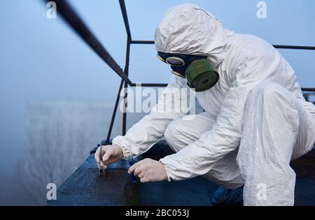 Worker collecting samples for analysis by tweezers in contaminated area, close-up side view snapshot, environment pollution concept Stock Photo