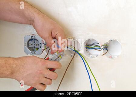 Electrician install outlets on beige wall with eu standards Stock Photo