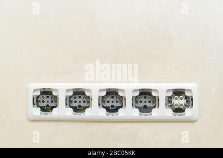 White socket outlets on beige wall witout cover. copy space. eu standart electric outlets. Stock Photo