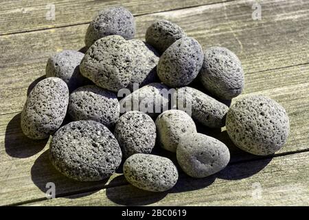 zen formation of lava pebbles on natural wooden floor, lava material mineral background concept Stock Photo