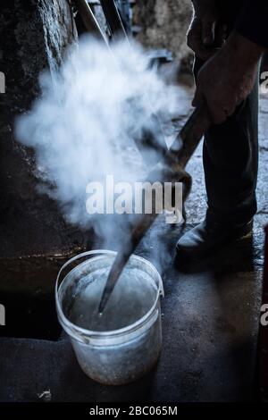 A pickaxe is cooled down in the smithy of the Hachlschmith in Josefsthal at Schliersee. The hammer smithy has existed for over 300 years and supplies not only regional woodworkers and forest farmers but also a large construction company with tools. [automated translation] Stock Photo