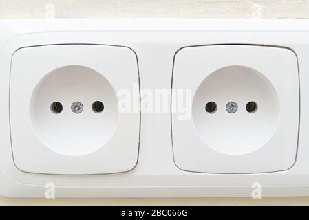 White socket outlets on beige wall. close - up eu standart electric outlets. Stock Photo