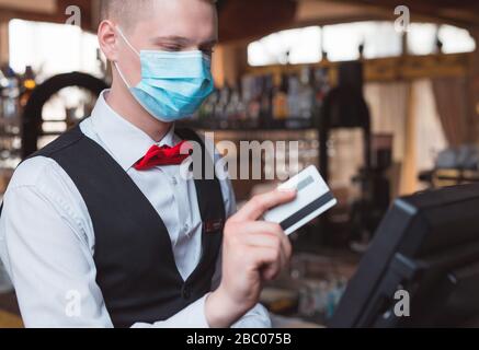 the waiter works in a restaurant in a medical mask Stock Photo