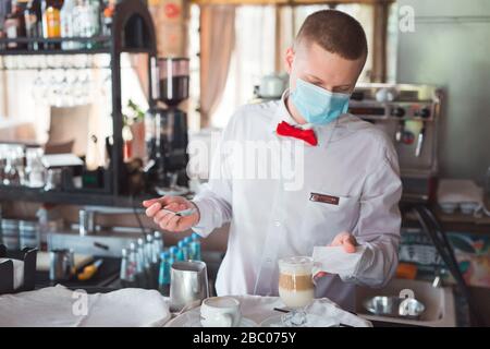 the waiter works in a restaurant in a medical mask Stock Photo