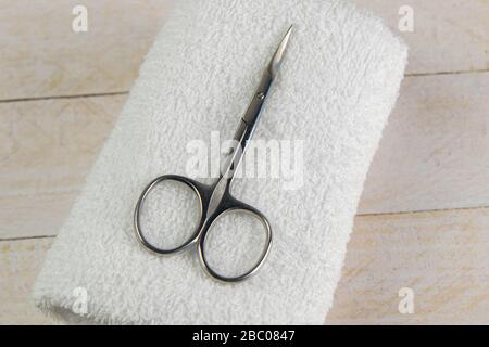 A set of cosmetic tools for manicure and pedicure on a blue background. The scissors of the manicure stand on a white towel on white wooden table Stock Photo