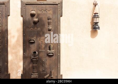 Carved old wooden door with hanging lantern on the wall. Stock Photo