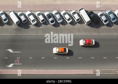 Two taxi cars on the road from above with parked cars on their right side. Stock Photo