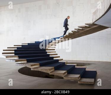 A lone man walks up the Modernist stairs seen inside Itamaraty Palace, Brazilia Stock Photo