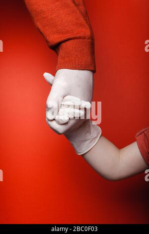 Dad and son are holding hands in disposable medical gloves. Quarantine Concept Stock Photo