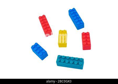 Six different colored building blocks scattered across an empty white isolated background Stock Photo