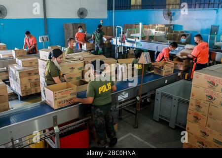 (Pasay City, Pasay City. 2nd Apr, 2020. Members of the Philippine Coast Guard, policemen and volunteers wearing face masks prepare relief goods as aid for communities under enhanced community quarantine at a government warehouse in Pasay City, the Philippines on April 2, 2020. The Philippines on Thursday required all those living in areas under enhanced community quarantine to wear face masks or other forms of protective equipment when they leave their homes to slow the spread of COVID-19. Credit: Xinhua/Alamy Live News Stock Photo