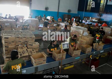 (Pasay City, Pasay City. 2nd Apr, 2020. Members of the Philippine Coast Guard, policemen and volunteers wearing face masks prepare relief goods as aid for communities under enhanced community quarantine at a government warehouse in Pasay City, the Philippines on April 2, 2020. The Philippines on Thursday required all those living in areas under enhanced community quarantine to wear face masks or other forms of protective equipment when they leave their homes to slow the spread of COVID-19. Credit: Xinhua/Alamy Live News Stock Photo