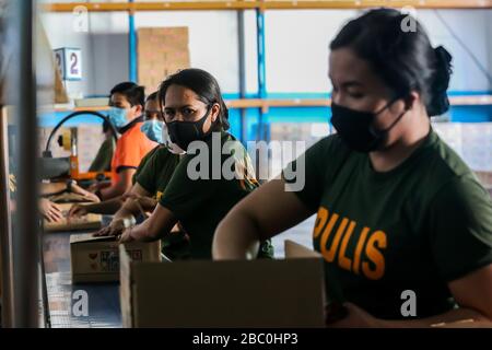 (Pasay City, Pasay City. 2nd Apr, 2020. Members of the Philippine Coast Guard, policemen and volunteers wearing face masks prepare relief goods as aid for communities under enhanced community quarantine at a government warehouse in Pasay City, the Philippines on April 2, 2020. The Philippines on Thursday required all those living in areas under enhanced community quarantine to wear face masks or other forms of protective equipment when they leave their homes to slow the spread of COVID-19. Credit: Xinhua/Alamy Live News Stock Photo