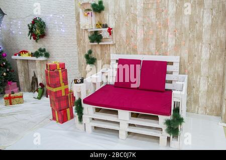 Interior of a New Year's photo studio with a tree.Beautiful Christmas decorated room with Christmas tree with presents under it. Red carpet. Yellow Stock Photo