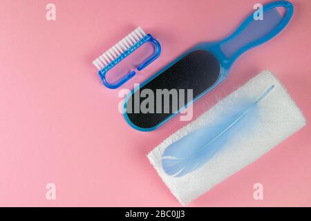 The concept of beautiful and healthy feet. Pedicure brush, foot stone and white towels with blue pen on a pink background. Top views with clear space Stock Photo