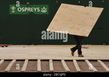 Workers lay flooring during the construction of a field hospital, which will hold up to 340 beds for coronavirus patients, at Llandarcy Academy of sport, Neath, as the health services in the Swansea Bay area prepare their response to the coronavirus outbreak. Stock Photo