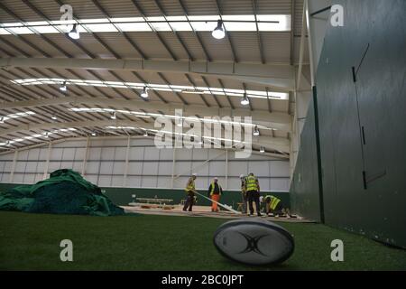 A discarded rugby ball and nets as workers lay flooring during the construction of a field hospital, which will hold up to 340 beds for coronavirus patients, at Llandarcy Academy of Sport, Neath, as the health services in the Swansea Bay area prepare their response to the coronavirus outbreak. Stock Photo