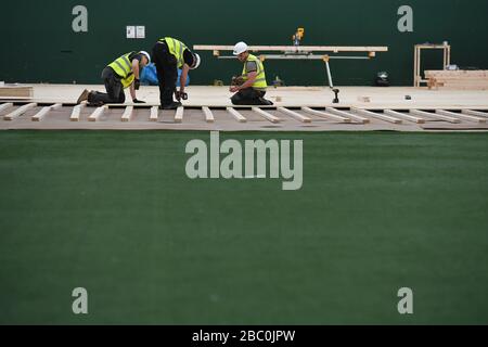 Workers lay flooring during the construction of a field hospital, which will hold up to 340 beds for coronavirus patients, at Llandarcy Academy of Sport, Neath, as the health services in the Swansea Bay area prepare their response to the coronavirus outbreak. Stock Photo