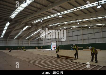 Workers lay flooring during the construction of a field hospital, which will hold up to 340 beds for coronavirus patients, at Llandarcy Academy of sport, Neath, as the health services in the Swansea Bay area prepare their response to the coronavirus outbreak. Stock Photo