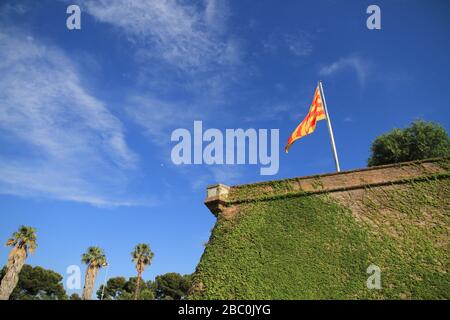 A view at the Catalonian Flag against a blue sky on the army fortress at Mont Juig, Barcelona, Catalonia, Spain. Stock Photo