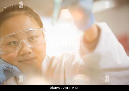 Pensive girl student conducting science experiment in classroom laboratory Stock Photo