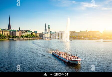 Classic panoramic view of famous Binnenalster (Inner Alster Lake) with fountain, tourist boat and the historic Hanseatic City of Hamburg