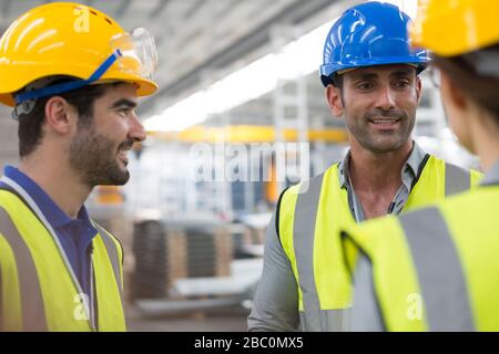 Smiling workers talking in factory Stock Photo