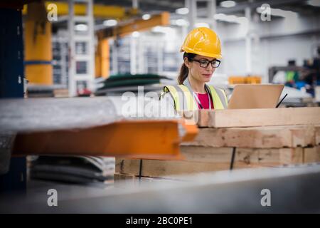 Female worker using laptop in factory Stock Photo