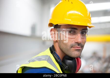 Portrait serious male worker in protective eyewear and hard-hat in factory Stock Photo
