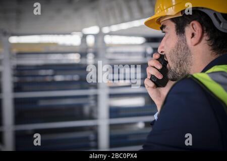 Male supervisor talking, using walkie-talkie in factory Stock Photo