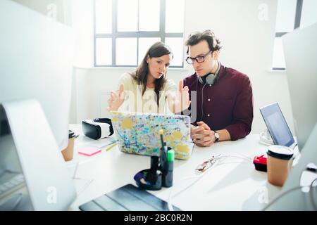 Designers brainstorming, gesturing at laptop in office Stock Photo