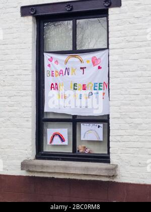 Bambrugge, Belgium, 30th Mar 2020: Window with collourful banner made by children to thank all those who help during the corona crisis. In Dutch. : Bedankt aan iedereen die helpt Stock Photo