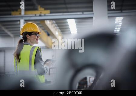 Confident female worker using digital tablet in steel factory Stock Photo