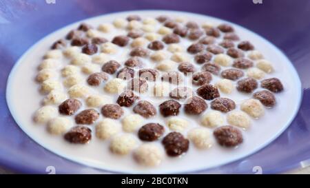 Healthy breakfast with milk on the table in a deep plate. Whole grain chocolate and milk balls. Healthy cereal breakfast. Children's breakfast. Baby Stock Photo