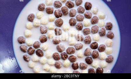 Healthy breakfast with milk on the table in a deep plate. Whole grain chocolate and milk balls. Healthy cereal breakfast. Children's breakfast. Baby Stock Photo