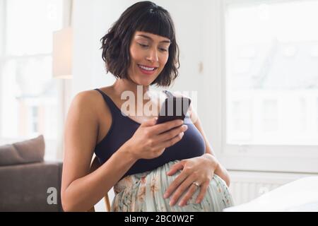 Happy pregnant woman using smart phone Stock Photo