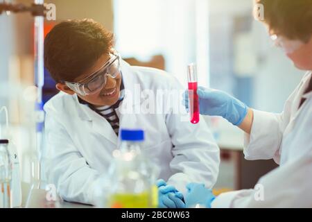 Boy students examining liquid in test tube, conducting scientific experiment in laboratory classroom Stock Photo