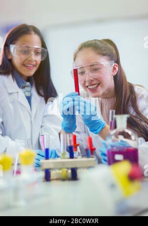 Smiling girl students examining liquid in test tube, conducting scientific experiment in laboratory classroom Stock Photo