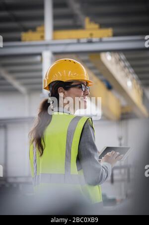 Confident, smiling female worker using digital tablet in factory Stock Photo