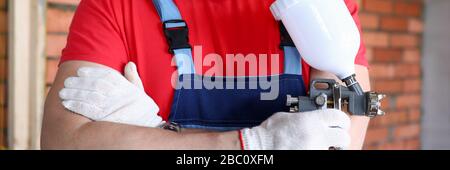 Close-up builder holding spray gun in his hands Stock Photo