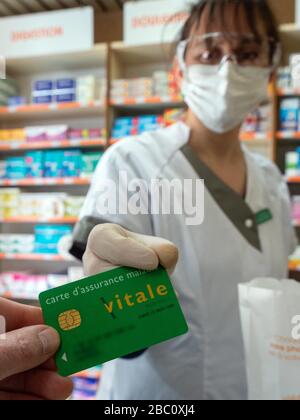 CUSTOMER AND PHARMACIST EXCHAGING THE CARTE VITALE (HEALTH INSURANCE CAED), PREVENTIVE HEALTH MEASURE PUT IN PLACE FOR THE CORONAVIRUS EPIDEMIC, RUGLES, NORMANDY, FRANCE Stock Photo