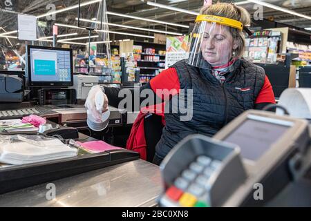 CLEANING OF THE CASH REGISTER AND CREDIT CARD TERMINAL AFTER EACH CUSTOMER, CASHIER AT A SUPERMARKET WEARING A PROTECTIVE FACE MASK AND GLOVES, CORONAVIRUS EPIDEMIC, FRANCE