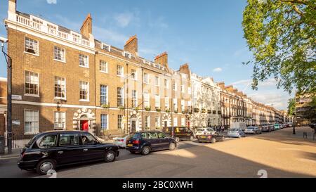 Bedford Square, Bloomsbury, London. A terraced row of grand Georgian town houses with contemporary traffic filling the narrow urban streets. Stock Photo