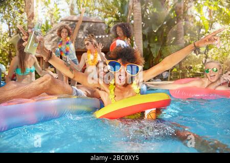 Portrait exuberant young friends drinking and playing in summer swimming pool Stock Photo